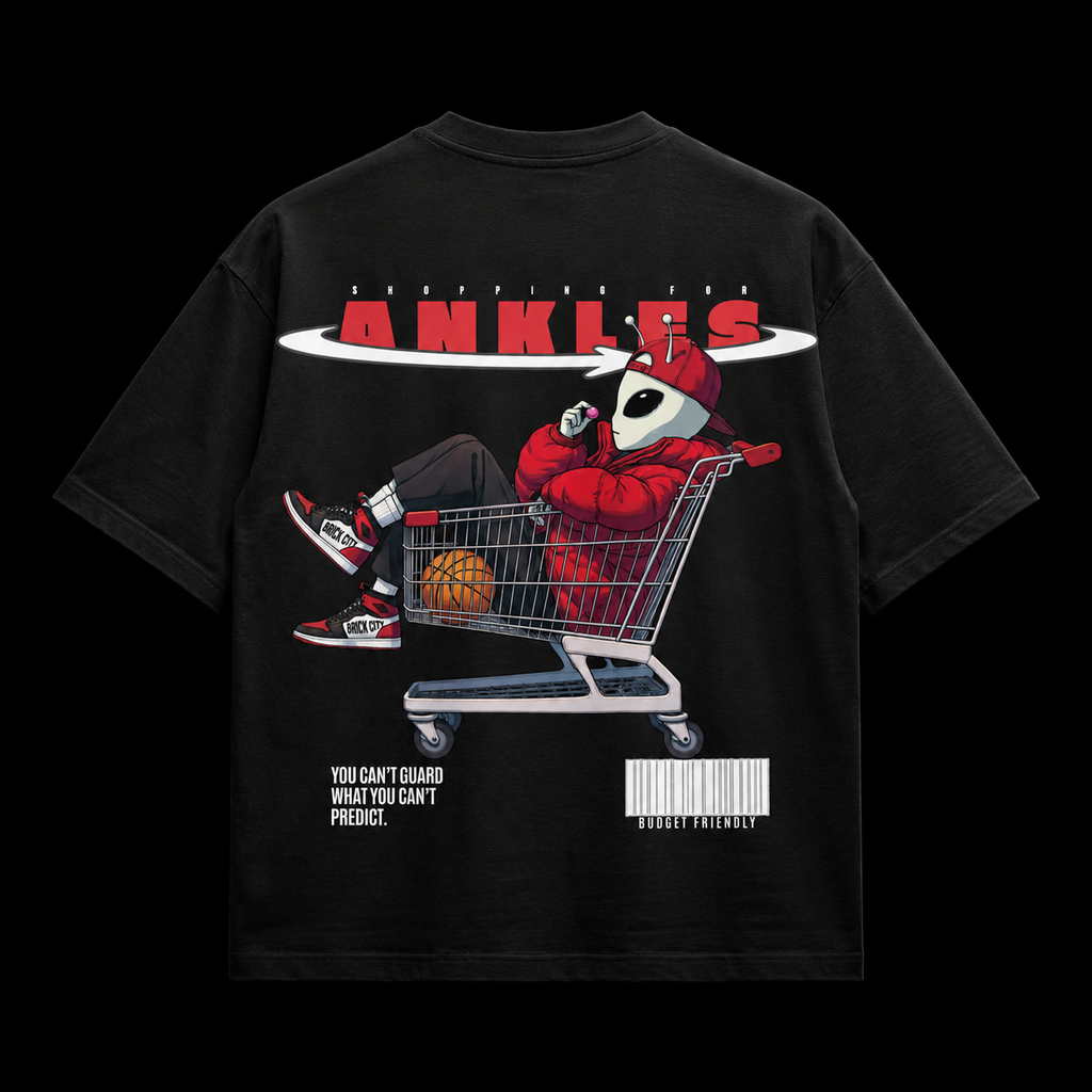 Black t-shirt with a graphic design of a person in a shopping cart with basketballs, wearing red sneakers and a red hoodie, on a black background.