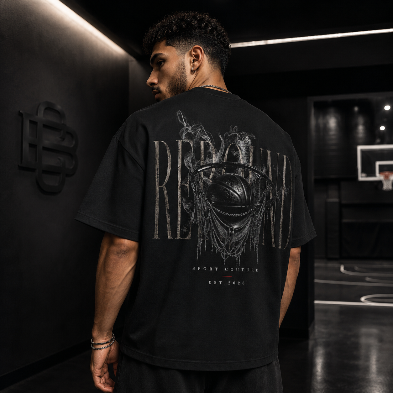 Man wearing a black t-shirt with a graphic design on the back in an indoor setting.