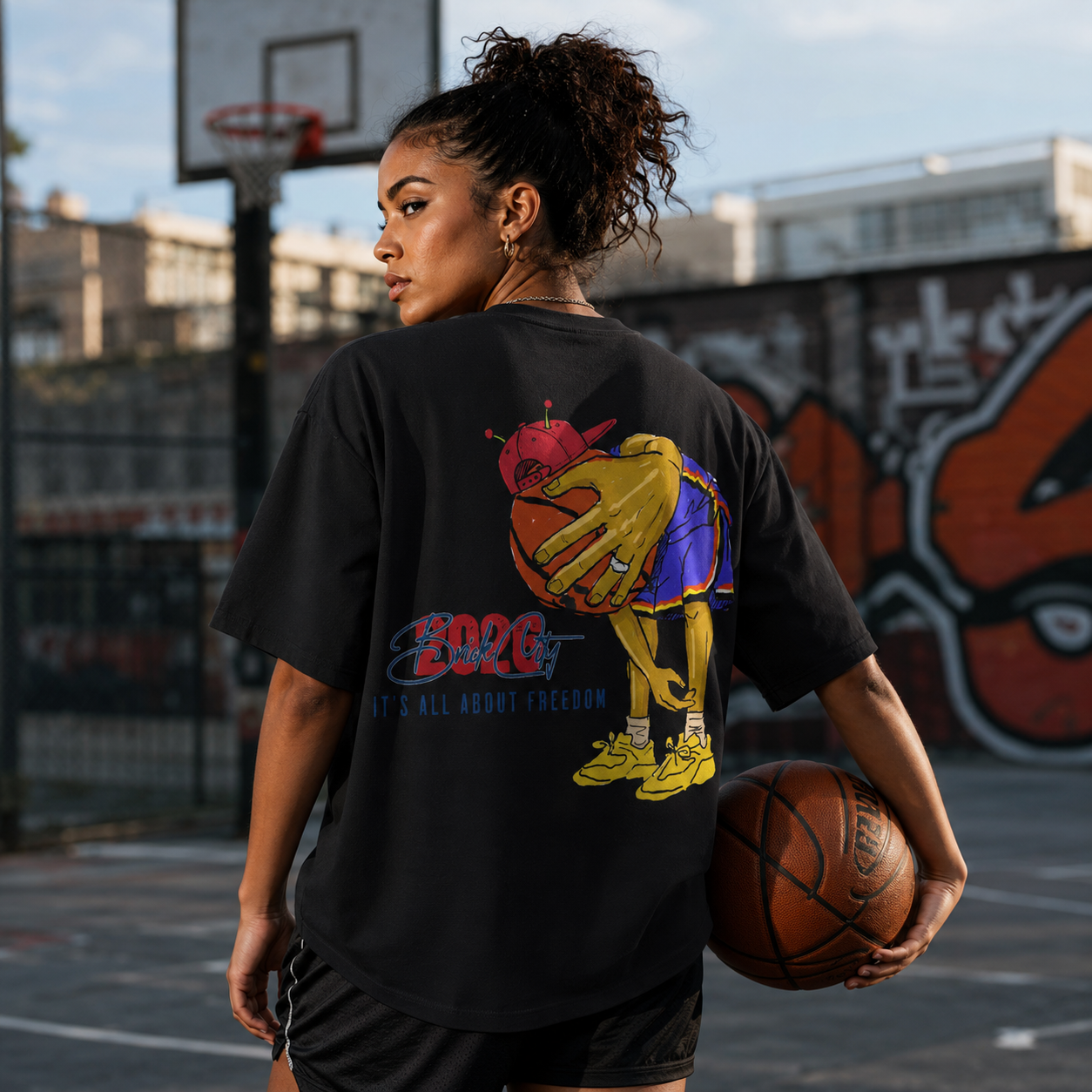 Person holding a basketball on a graffiti-covered outdoor court