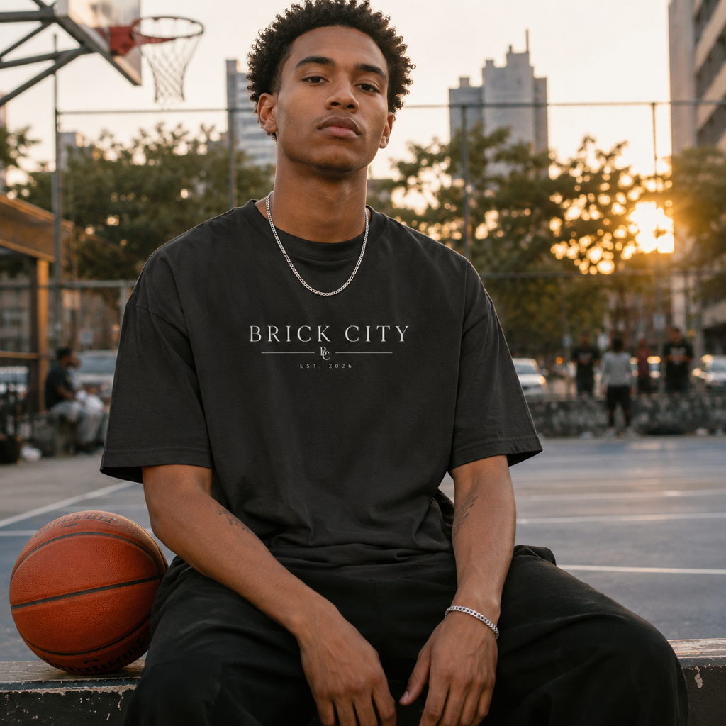 Person wearing a 'Brick City' t-shirt on an outdoor basketball court with sunset in the background
