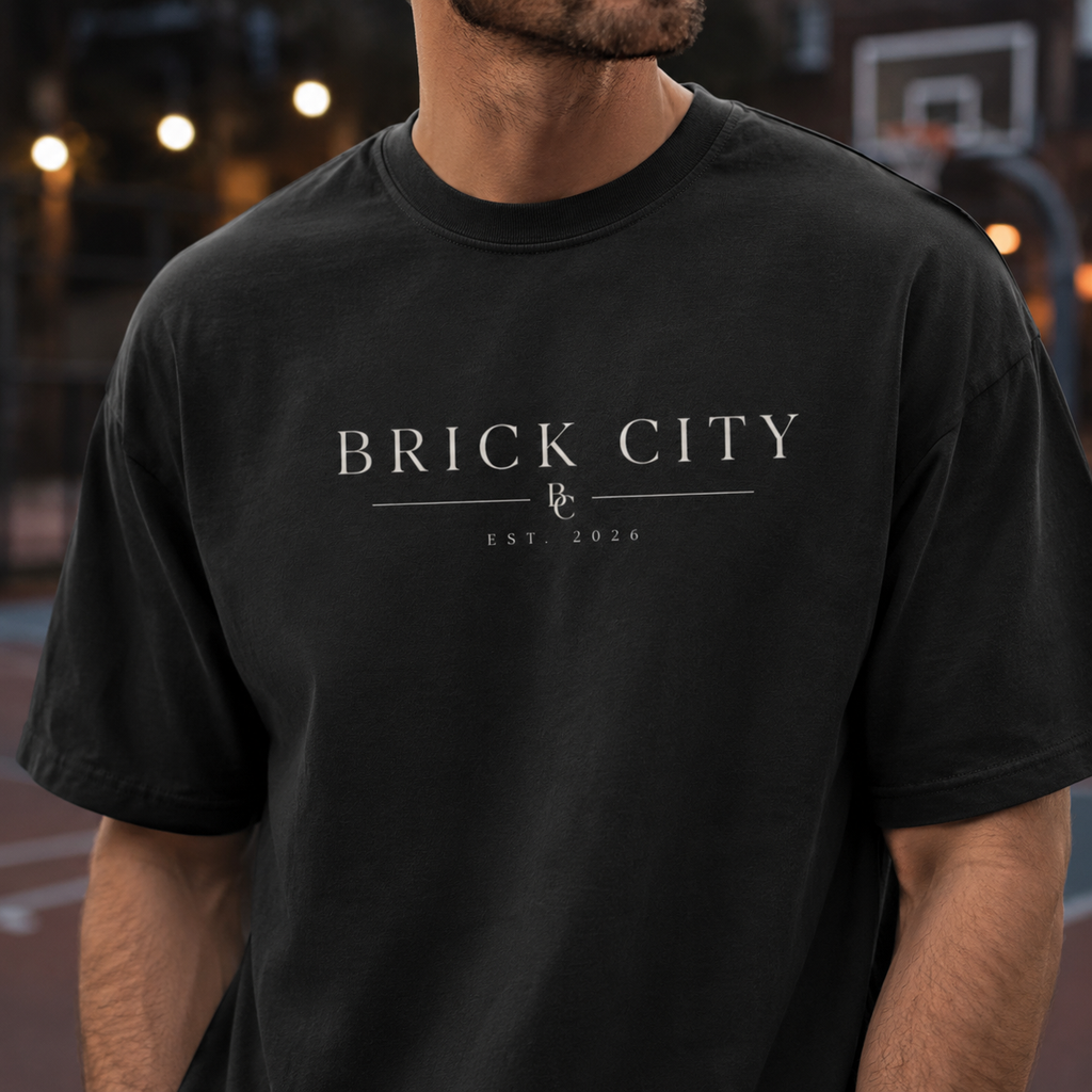 Person wearing a 'Brick City' t-shirt on an outdoor basketball court with sunset in the background