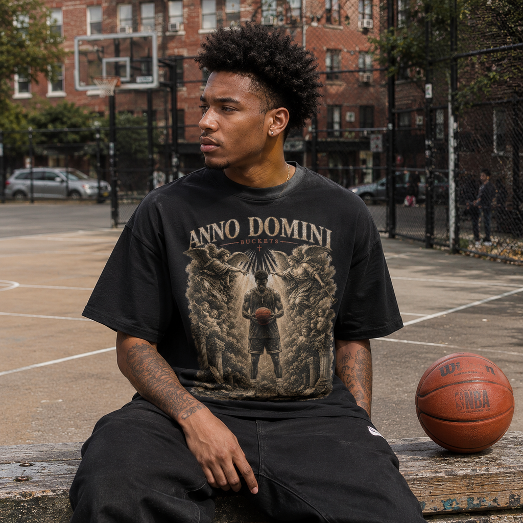Person wearing a black Bucket Getter t-shirt sitting on a basketball court