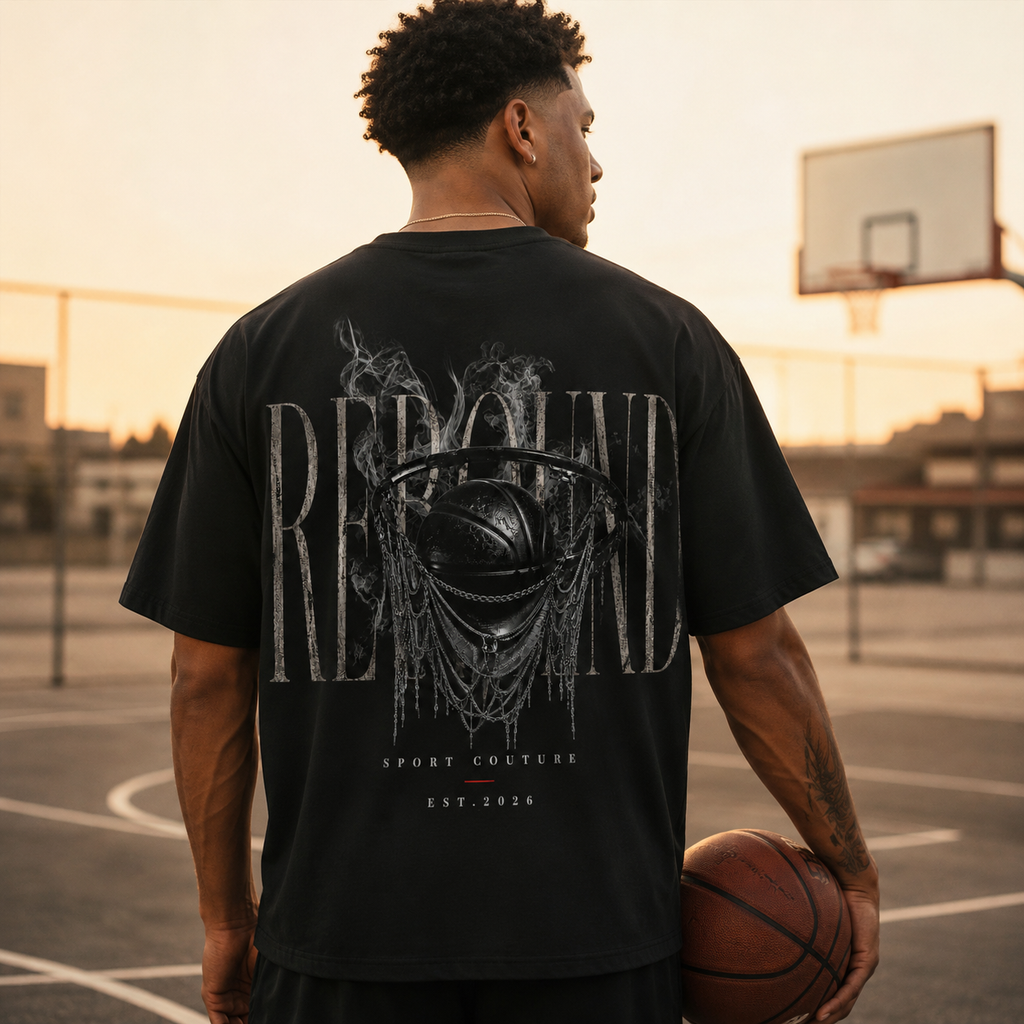 Person wearing a black t-shirt with 'Rebound' design on a basketball court at sunset.