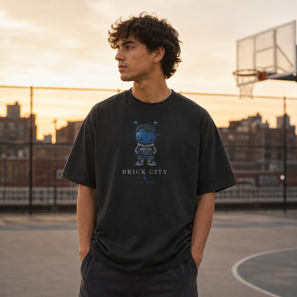 Person wearing a black t-shirt with a graphic design on a basketball court at sunset.