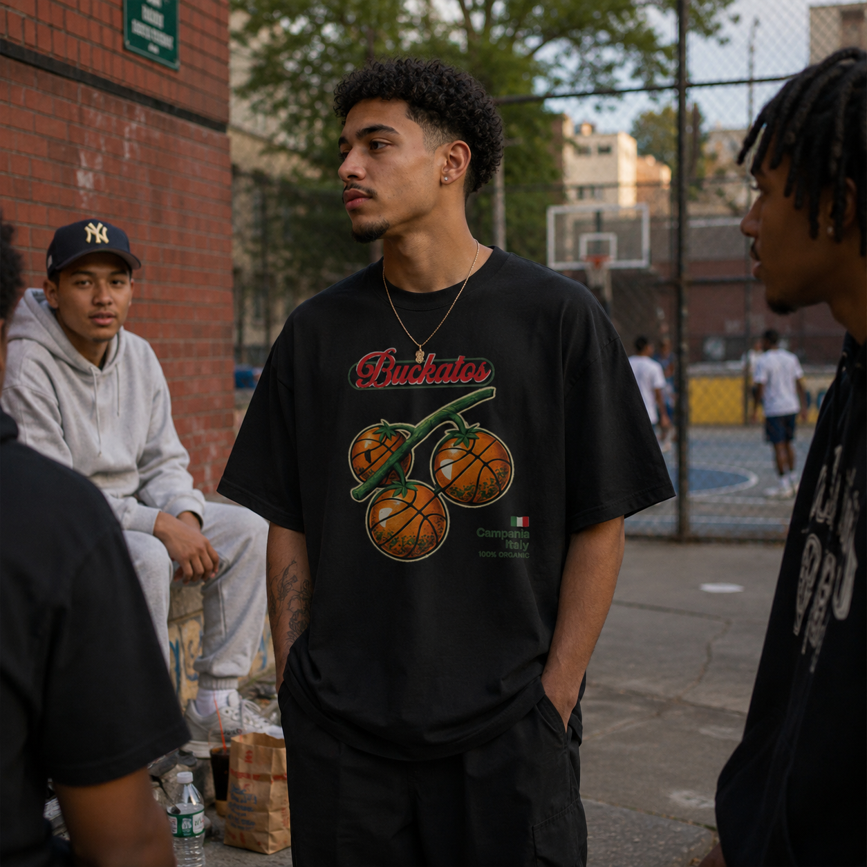 Person wearing a black t-shirt with a graphic design, standing on a street with others in the background.