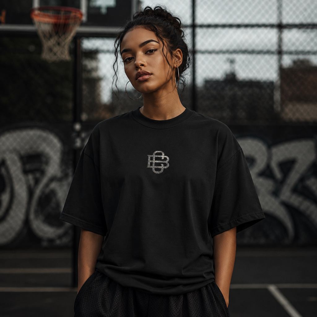 Person wearing a black t-shirt with a logo on a basketball court