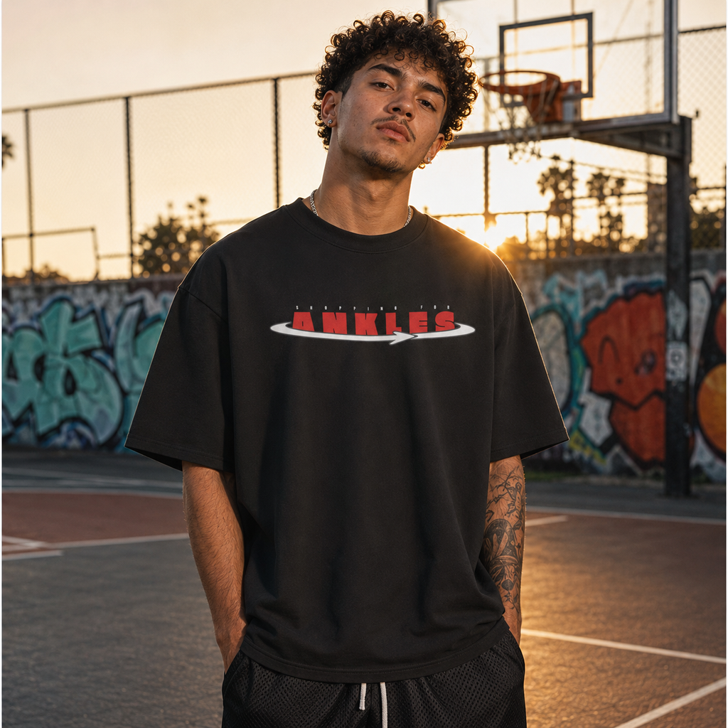 Person wearing a black t-shirt with red and white text on a basketball court with graffiti in the background.