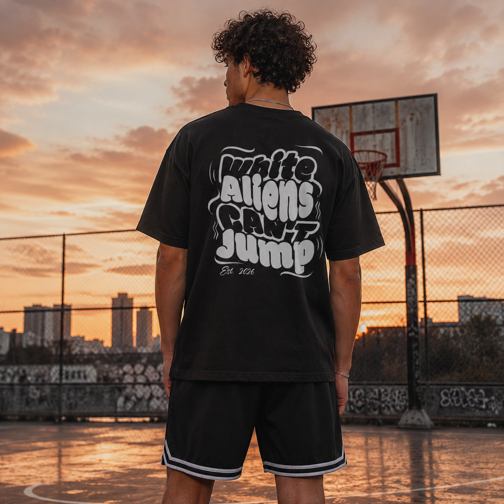Person wearing a black t-shirt with white text on a basketball court at sunset.