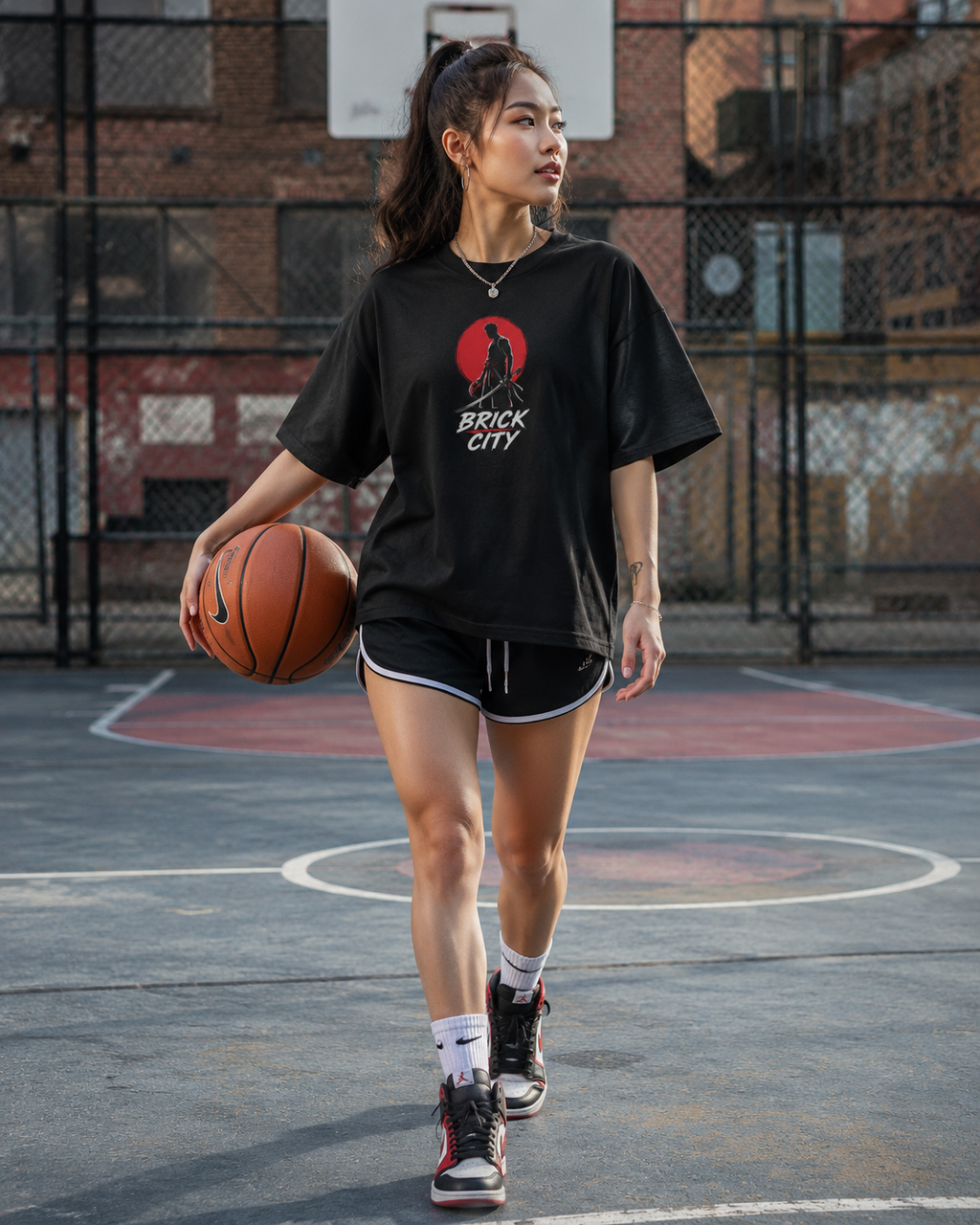 Woman holding a basketball on a basketball court with 'Brick City' t-shirt