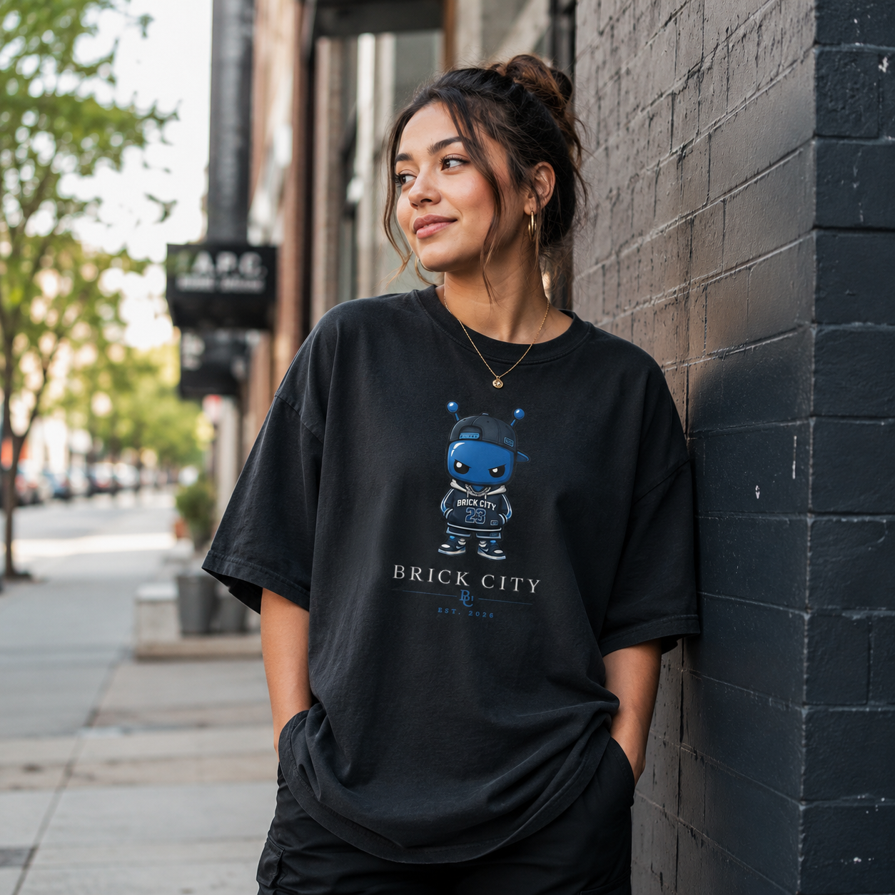 Woman wearing a black t-shirt with a graphic design leaning against a brick wall.