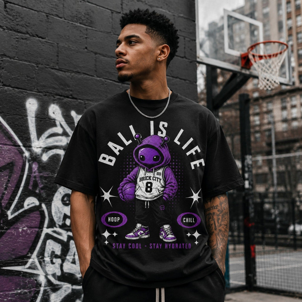 Model wearing Ball Is Life Brick Tee beside outdoor urban basketball court