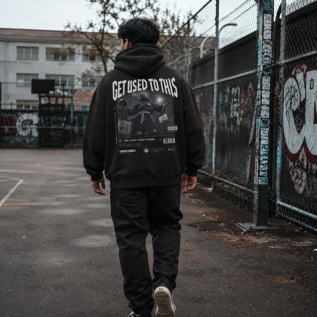 Man wearing Get Used To This hoodie back print walking past a graffiti basketball court