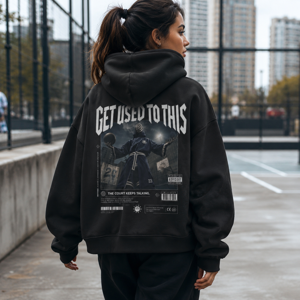 Woman wearing Get Used To This hoodie back graphic on an outdoor basketball court