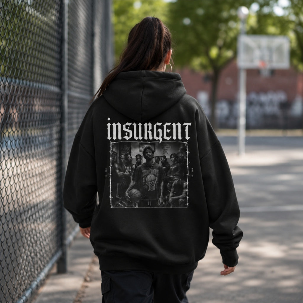 Woman wearing Insurgent hoodie back graphic walking beside a basketball court
