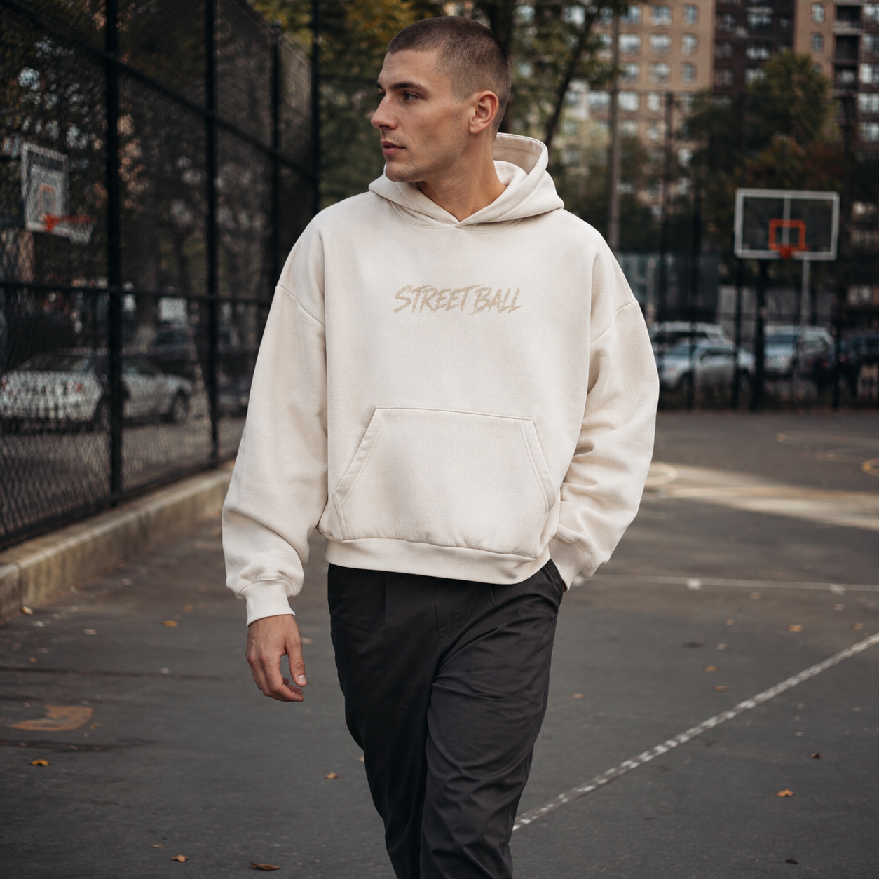 Man wearing light beige Streetball hoodie front print on an outdoor basketball court