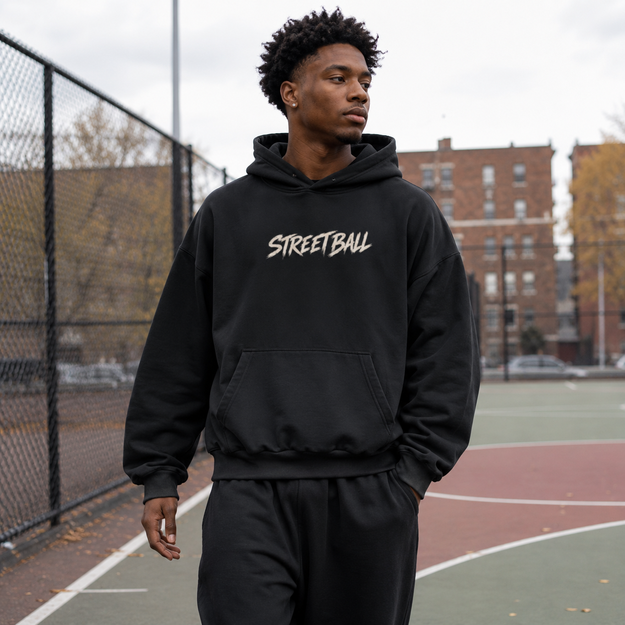 Man wearing black Streetball hoodie front print on an outdoor basketball court